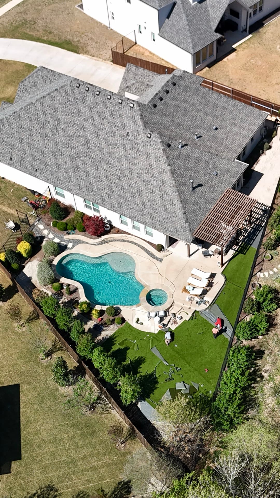 Aerial drone photo of suburban home with pool and turf backyard